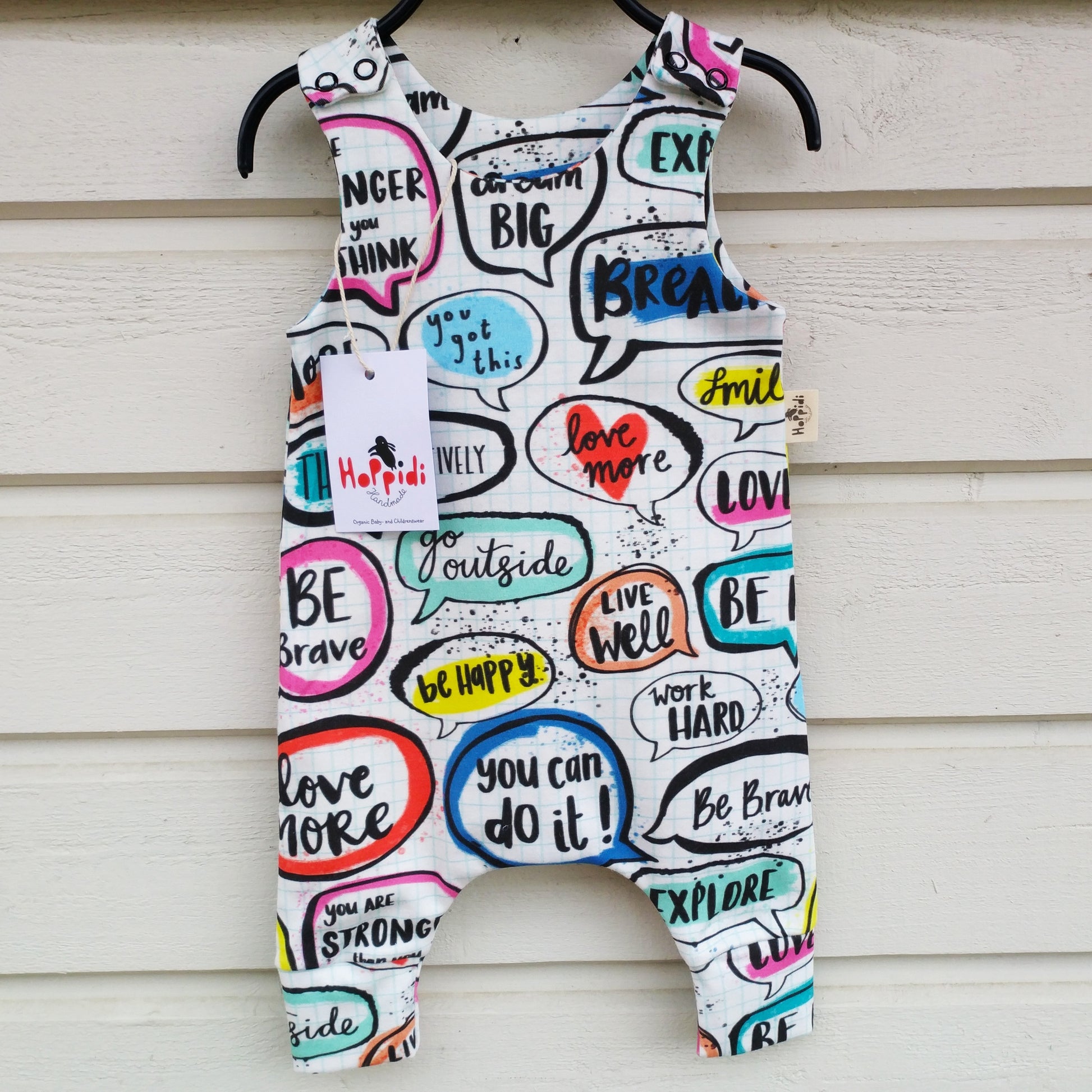 Harem style baby romper with colorful pattern showing speech bubbles drawn on a notebook page with positve affirmations written in them