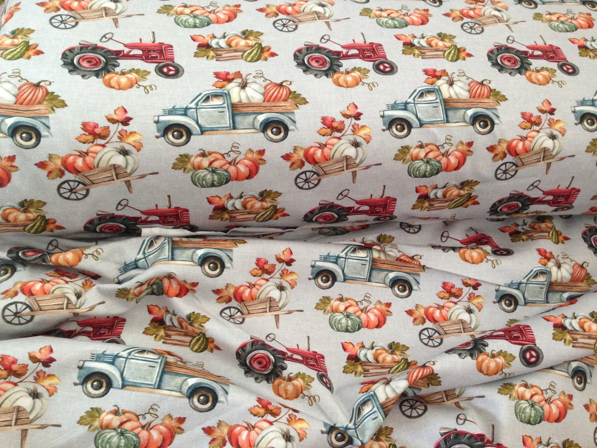 Organic jersey fabric with grey burlap cloth optic background and trucks, tractors, wheelbarrows and wooden boxes filled with pumpkins pattern.