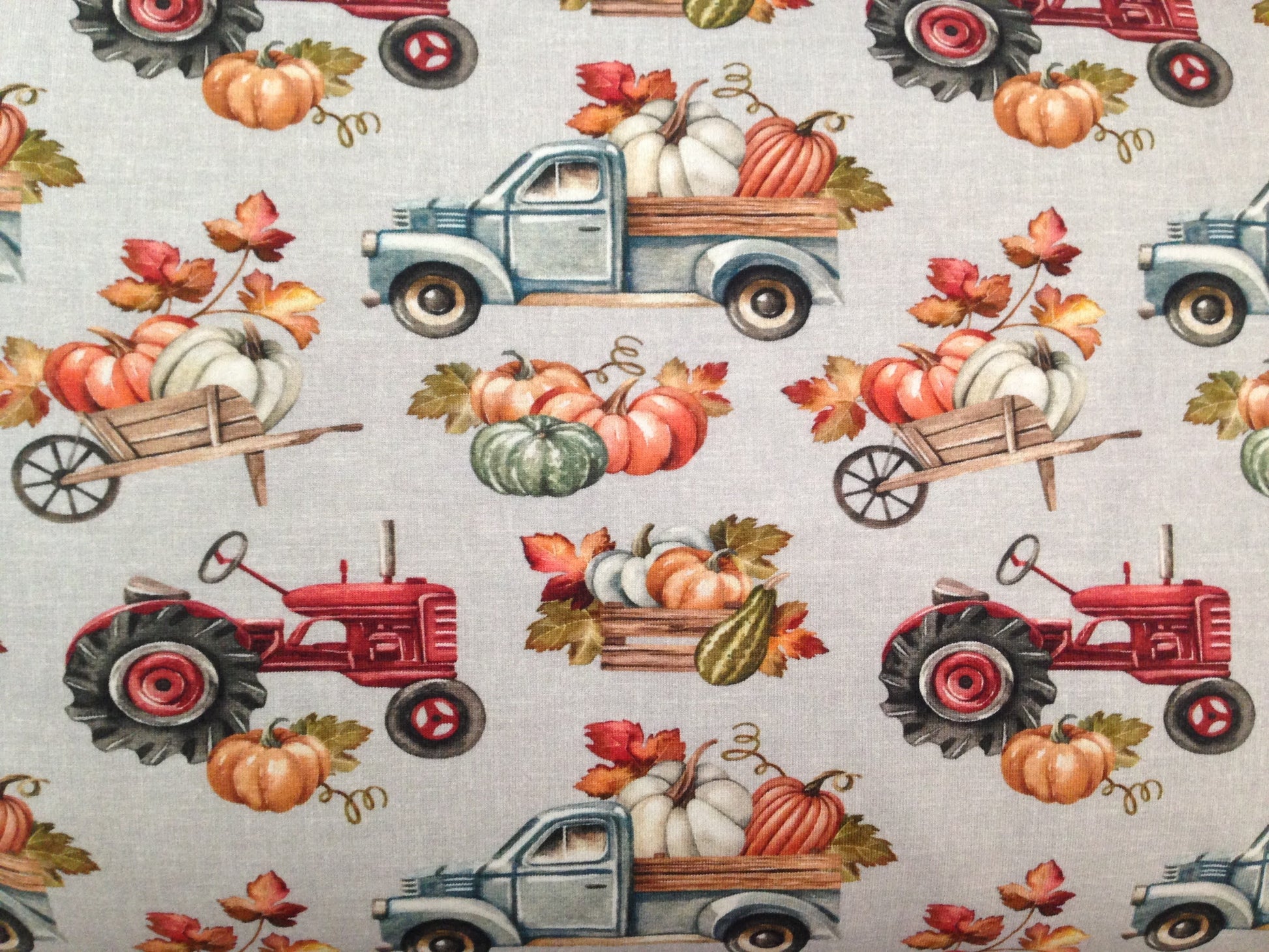 Organic jersey fabric with grey burlap cloth optic background and trucks, tractors, wheelbarrows and wooden boxes filled with pumpkins pattern.